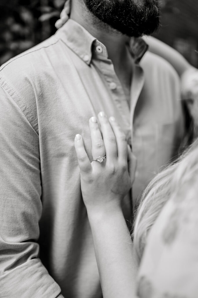 Black and white close up photo of woman's hand with engagement ring