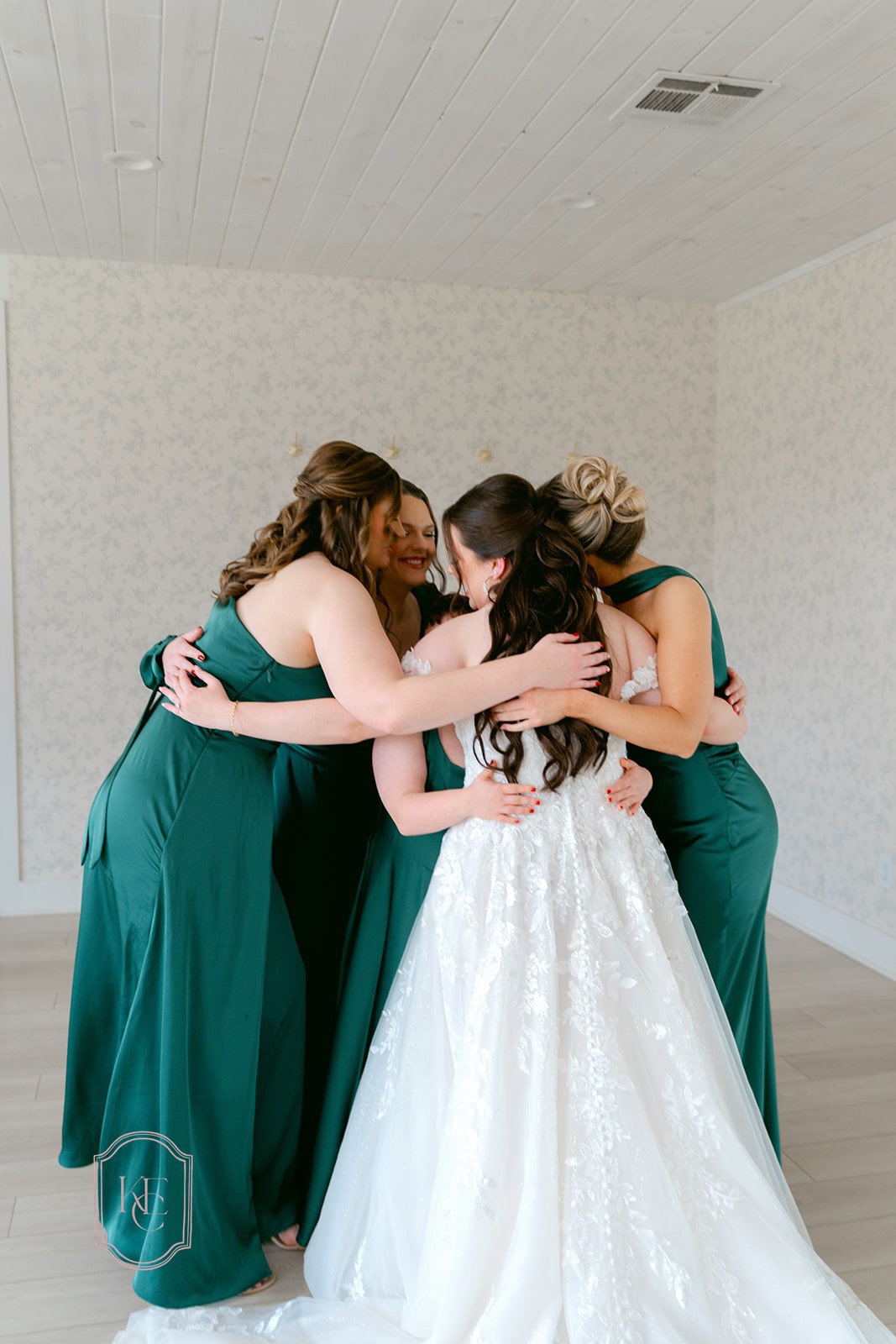 Bride and bridesmaids hug indoors