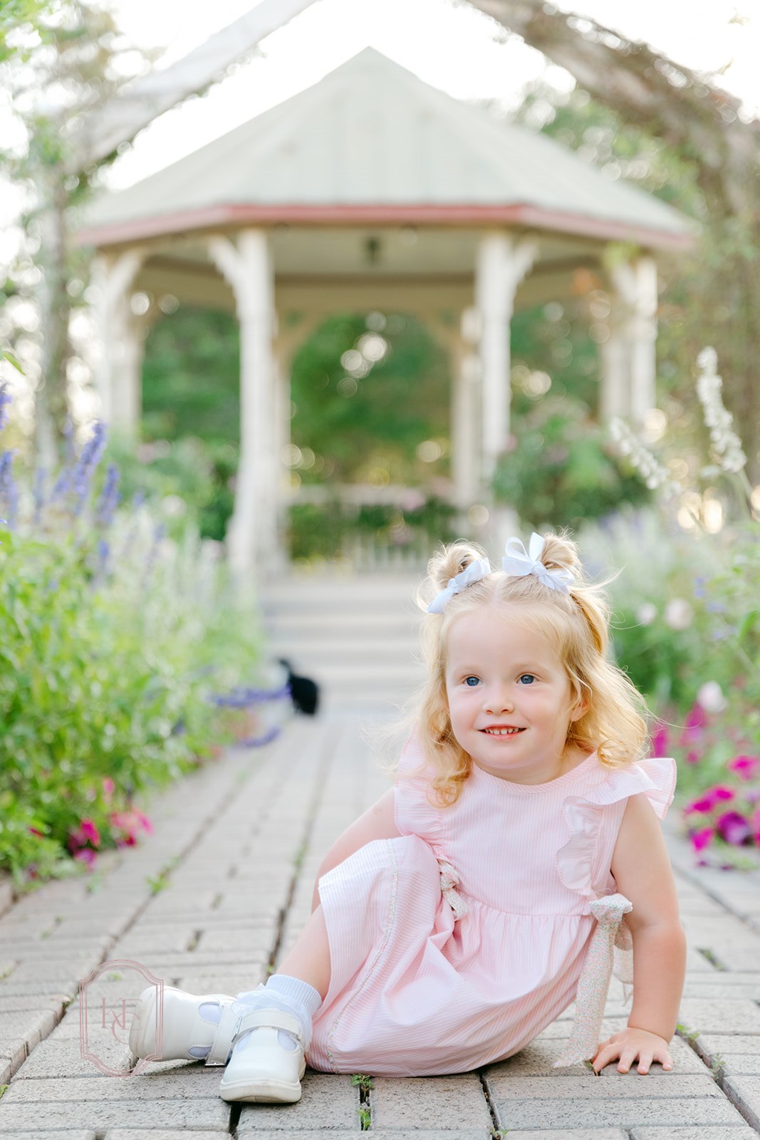 Little girl sits and smiles at The Antique Rose Emporium