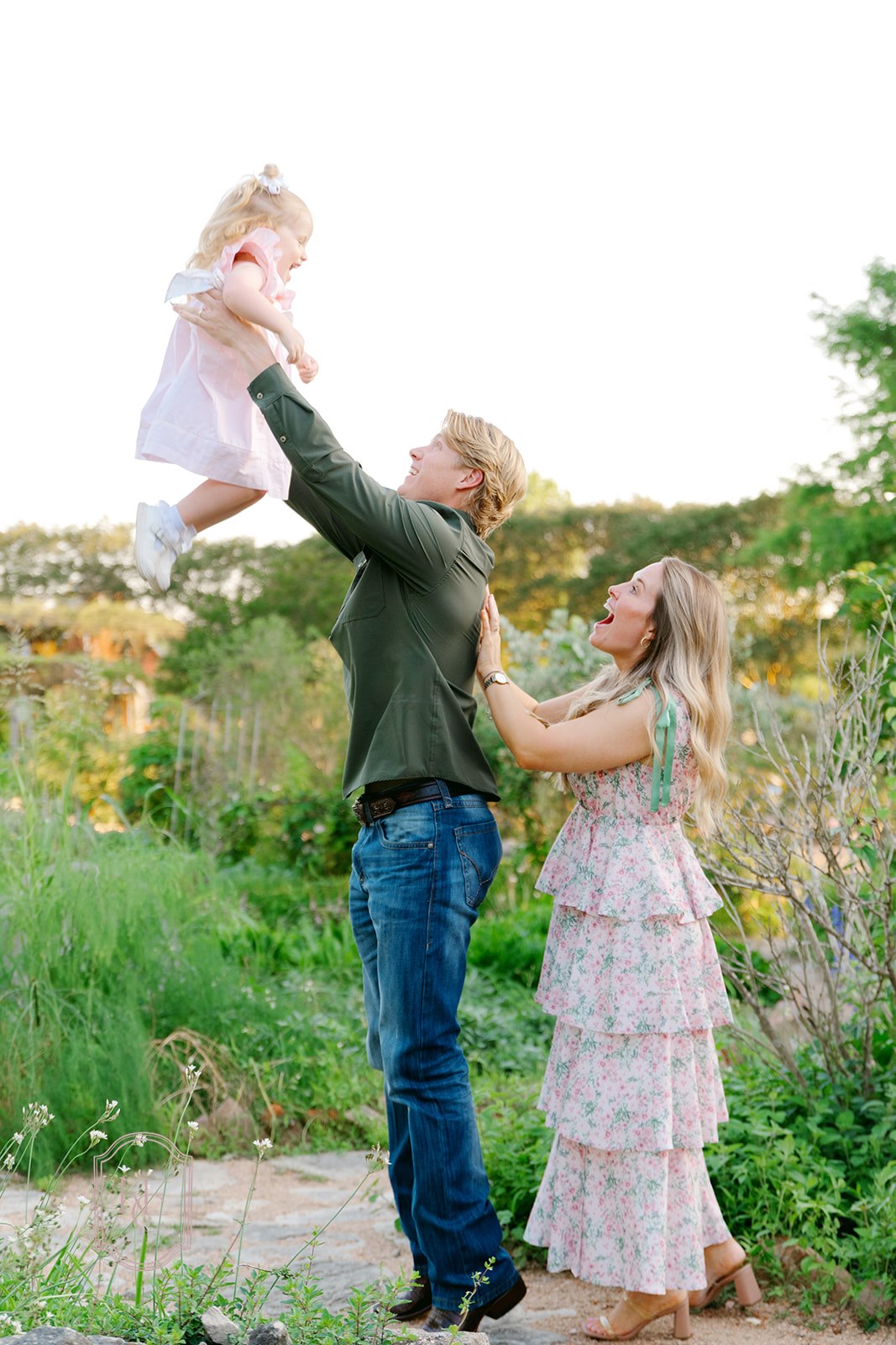 Man holds toddler up in the air at The Antique Rose Emporium