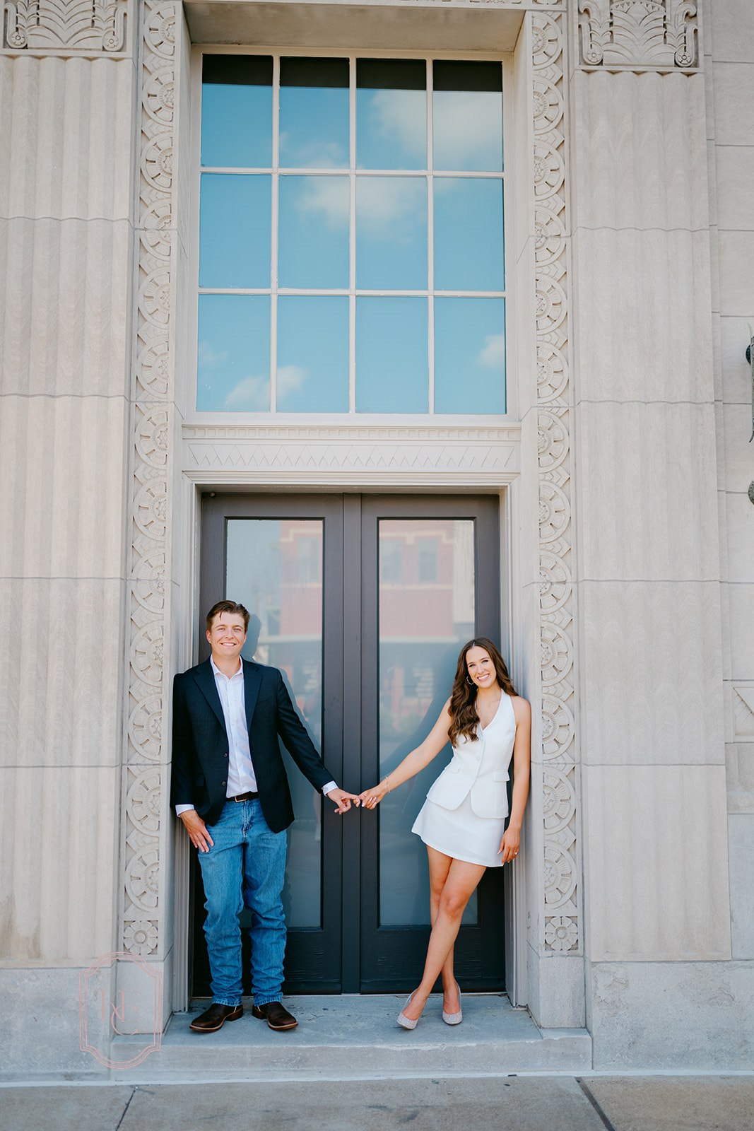 Couple holds hands and poses for outdoor engagement photos