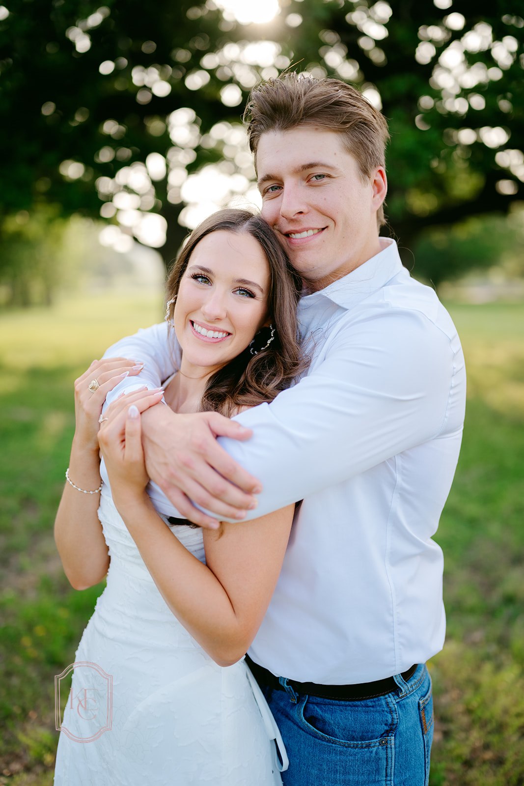 Man and woman smile at the camera during outdoor engagement photos